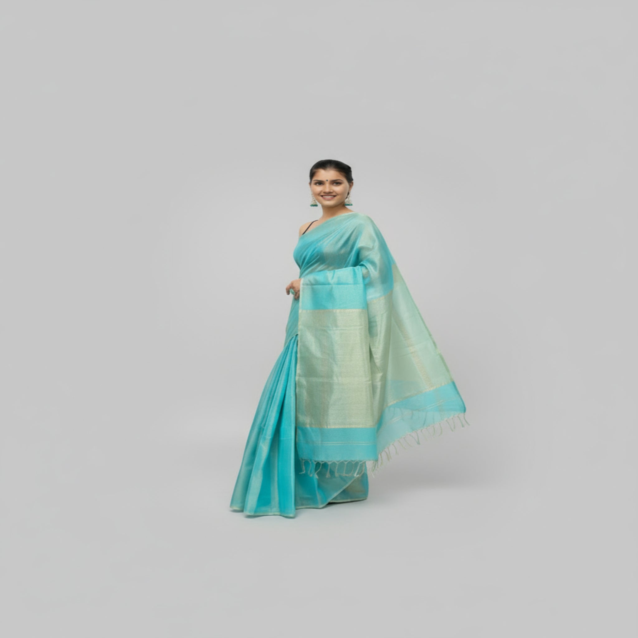 A woman wearing a sky blue Maheshwari Tissue Saree with golden zari border and cotton weft, handwoven in Maheshwar, showcasing elegant traditional Indian handloom craftsmanship.