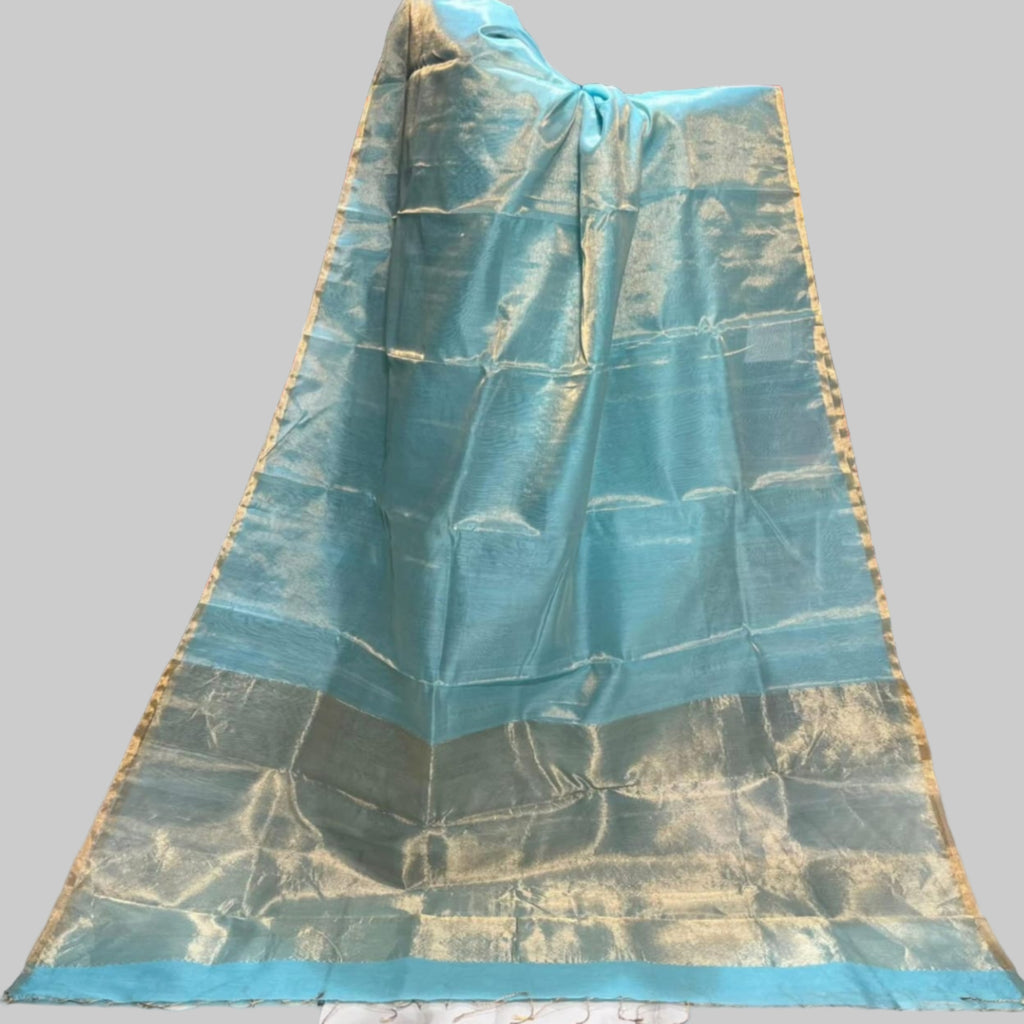 Aqua blue Maheshwari Tissue Saree with golden zari border and shimmering texture, handwoven in Maheshwar, displayed elegantly in a saree showroom showcasing traditional Indian craftsmanship.